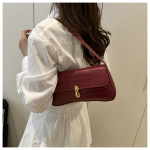 Detail of deep red crocodile pattern leather bag with elegant golden metal lock clasp
