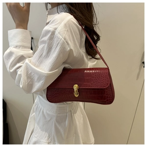 Detail of red crocodile texture underarm bag with golden buckle on a white dress model