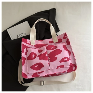 Détail du cabas en toile rose avec taches abstraites rouges et structure multi-poches