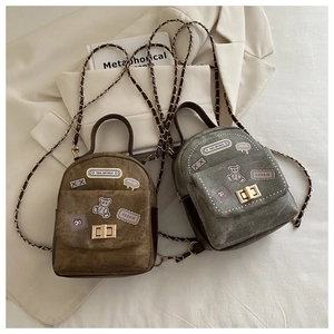 Detail of mini canvas backpacks with trendy patches and elegant gold twist lock closure