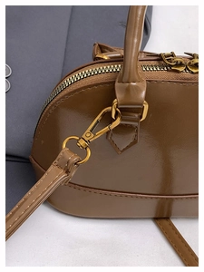 Détail du sac coque marron montrant la texture du cuir et les fermetures dorées