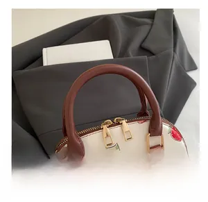 Gros plan du sac à main imprimé fraises avec anses en cuir marron et zips dorés