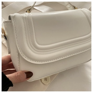 Détail du sac à bandoulière blanc avec coutures en U parallèles et boucle dorée