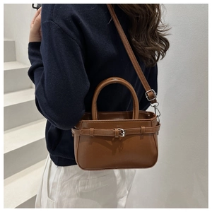 Detail of dark brown leather bucket bag with metal buckle strap and shoulder handle