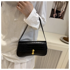 Detail of black crocodile embossed baguette bag featuring a gold buckle on the shoulder