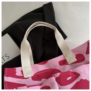 Macro shot of reinforced X-shape stitching on the durable straps of pink leopard tote bag