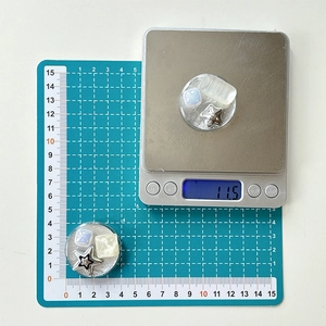 Detail shot of heart star rhinestone phone grip showing 11.5g weight on a scale