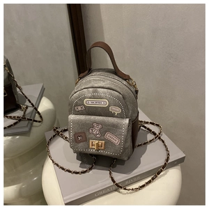 Detail of grey denim mini backpack with leather handle and decorative bear patches