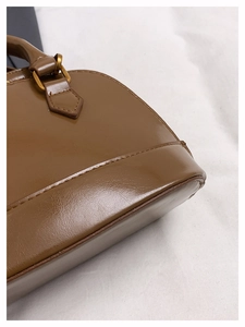 Détail du sac bandoulière marron montrant les coutures fines et les ferrures dorées