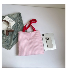 Vue détaillée du sac cabas en toile à rayures roses avec anses rouges et accessoires urbains
