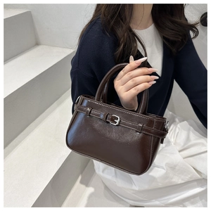 Close-up of brown glossy bucket bag with silver metal buckle and cylindrical handles