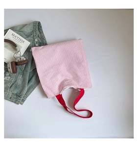 Vue lifestyle d'un sac cabas en toile rayé rose avec des anses rouges et des accessoires
