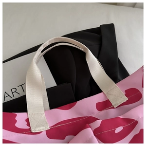Détail du sac cabas à motif rose avec coutures renforcées sur la bandoulière en toile