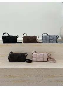 Collection of woven crossbody bags in five colors on a textured stone display