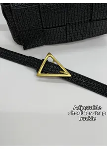 Close-up of adjustable shoulder strap buckle on black woven square crossbody bag