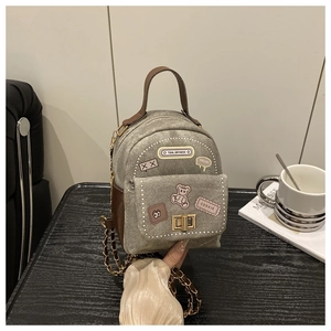 Detail of mini canvas backpack with bear embroidery, metal chain strap and twist lock