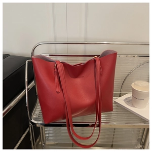 Detail of red faux leather tote bag with FASHION & BAGS print on a metal stand