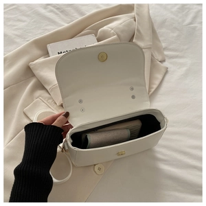 Vue détaillée de l'intérieur d'un sac bandoulière en cuir blanc avec fermoir doré