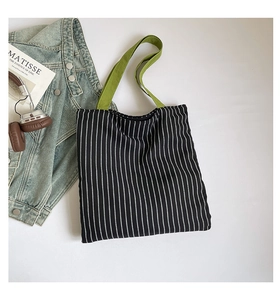 Détail d'un sac fourre-tout en toile à rayures noires et blanches avec des anses vertes