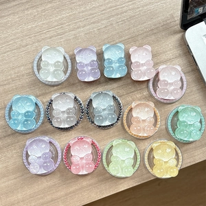 Glittery bear phone grips with pearls and colorful resin designs on a wooden surface