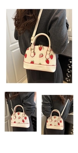 Détails du sac coquille à imprimé fraise avec finitions dorées et bandoulière réglable