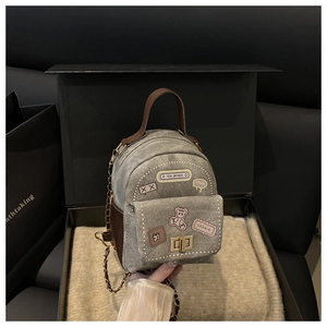 Detail of gray denim mini backpack with vintage patches, gold twist lock and chain strap