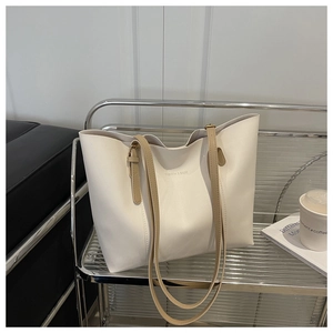 Detail of a large beige tote bag with khaki straps on a modern display stand