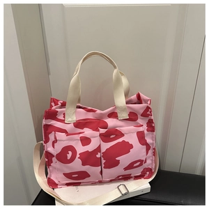 Détail du sac cabas en toile rose avec imprimés rouges abstraits et poches frontales