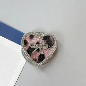 Detalle del soporte móvil de corazón con lazo de diamantes y estampado de leopardo