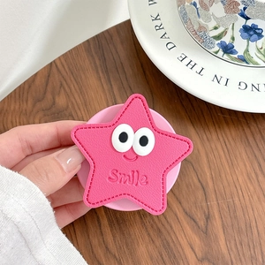 Gros plan d'un support de téléphone en cuir rose en forme d'étoile avec motif sourire