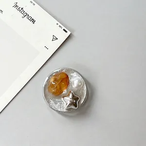 Detail of silver foil phone grip with amber resin, faux pearl, and star ornament