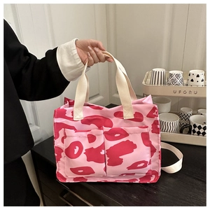 Détail du cabas en toile léopard rose avec doubles poches avant et larges anses crème