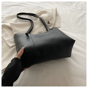 Dettaglio della borsa tote nera con cuciture rifinite su sfondo di moda elegante