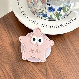 Support de téléphone en forme d'étoile rose avec smiley et coutures sur table