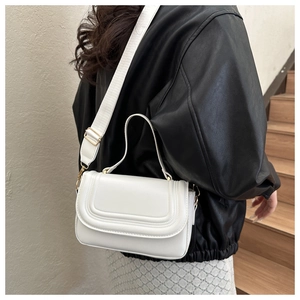 Détail du sac bandoulière blanc avec coutures incurvées, finitions dorées et large sangle