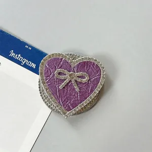 Detalle del soporte móvil de corazón púrpura con textura de cuero y lazo de diamantes