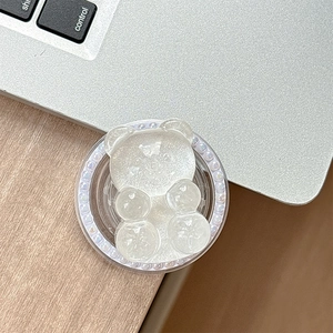 Detailed view of a glittery resin bear phone grip with colorful pearls on a laptop