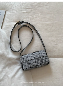 Close-up of retro black and white woven pattern and vintage gold buckle on a crossbody bag