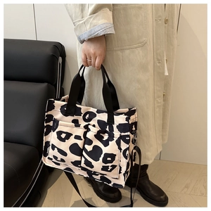 Chic cow print tote bag detail showing dual front pockets and woven handle on a trench coat