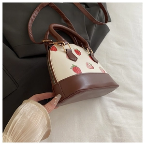 Dettaglio della stampa fragola sulla borsa beige con manici in pelle marrone