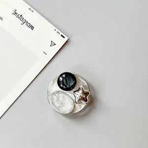Detail view of round silver phone grip with star accent and marble texture inlay