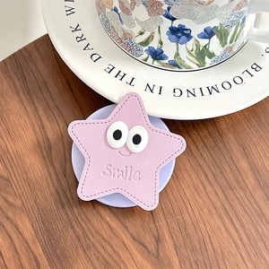 Support téléphone étoile rose brodé Smile sur table en bois avec décor céramique