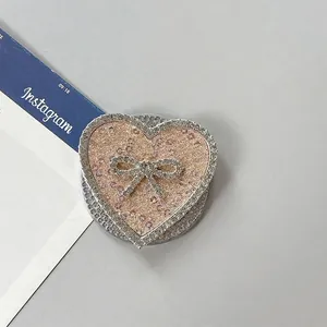 Detalle del soporte de móvil de corazón con purpurina oro rosa y lazo de diamantes