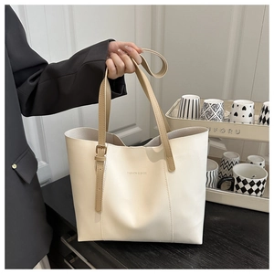 Detail of adjustable leather strap and letter print on a beige minimalist tote bag