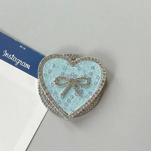 Detalle del soporte de móvil corazón azul claro con diamantes de imitación y lazo