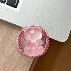 Detail of pink resin bear phone grip with glitter pearls on laptop surface