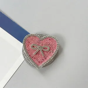Detalle macro de soporte para móvil corazón rosa brillante con pedrería y lazo de cristal