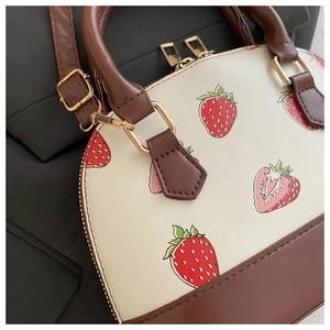 Detail view of cream handbag with cherry prints and high-quality gold zipper hardware
