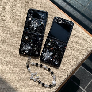 Detail view of black foldable phone case with silver glitter stars and pearl charm lanyard