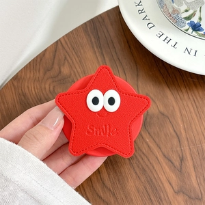 Gros plan d'un support de téléphone rouge en forme d'étoile avec motif sourire gravé